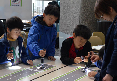 ペンライトを使ってソーラーミニカーを走らせる子供たち(市生涯学習フェスティバル「まなトピア」)