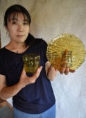 川湯温泉の天然成分が入ったガラス工芸品「川湯温泉ユノハナガラス」を手にする木名瀬さん
