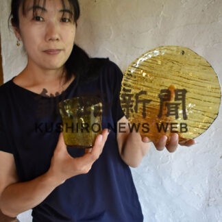 川湯温泉の天然成分が入ったガラス工芸品「川湯温泉ユノハナガラス」を手にする木名瀬さん